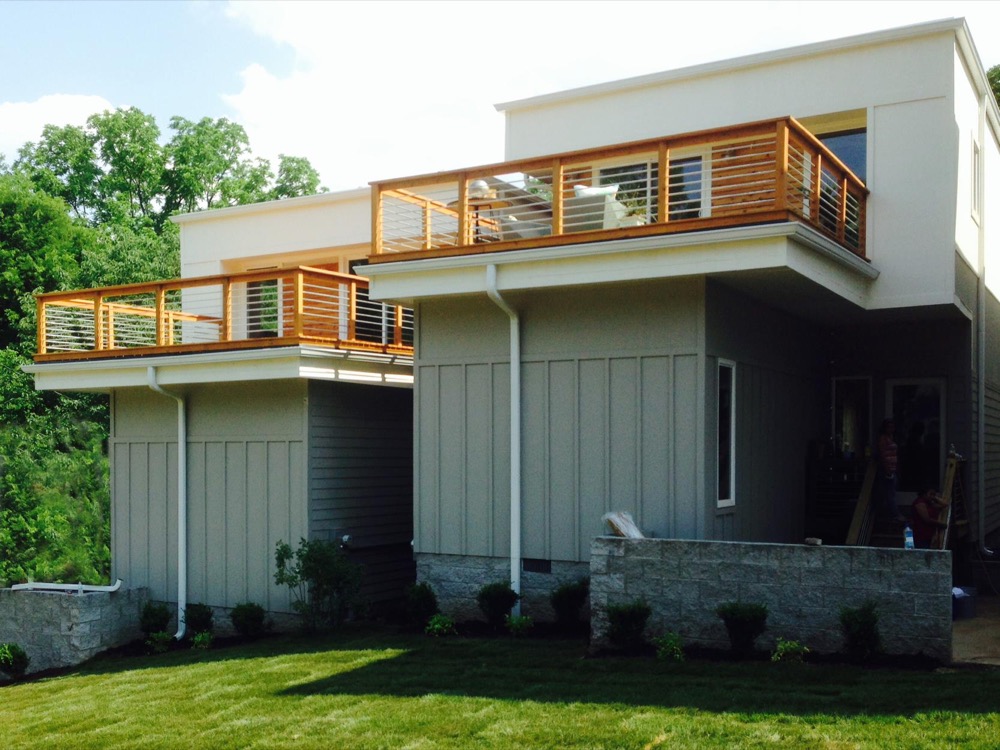 Modern two-story home in white and sage green with wood-rail balconies
