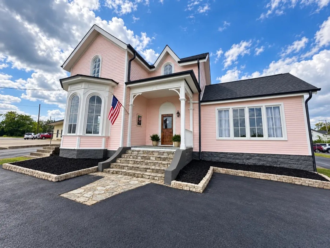 Pink two-story Victorian with white trim and a bay window