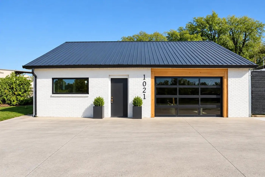 White painted brick building with a cedar-framed glass garage door